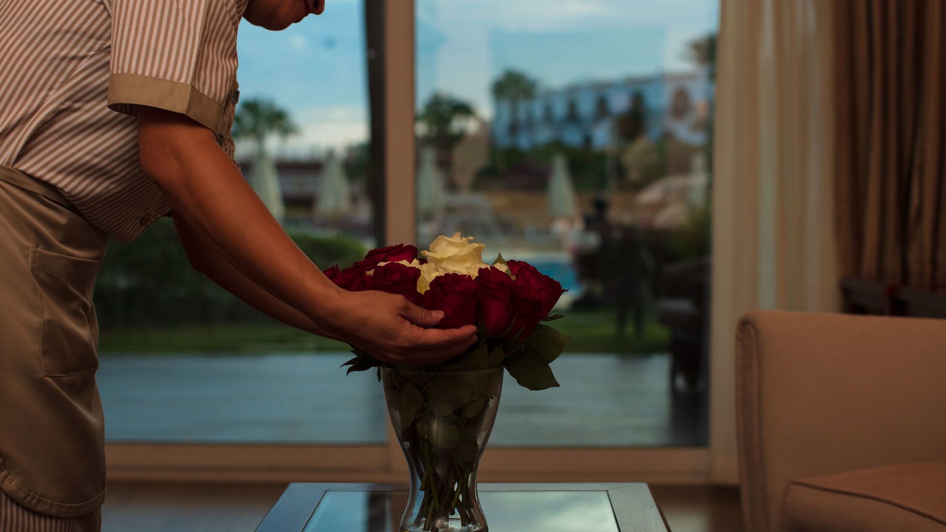 A Person Holding A Vase Of Flowers On A Table